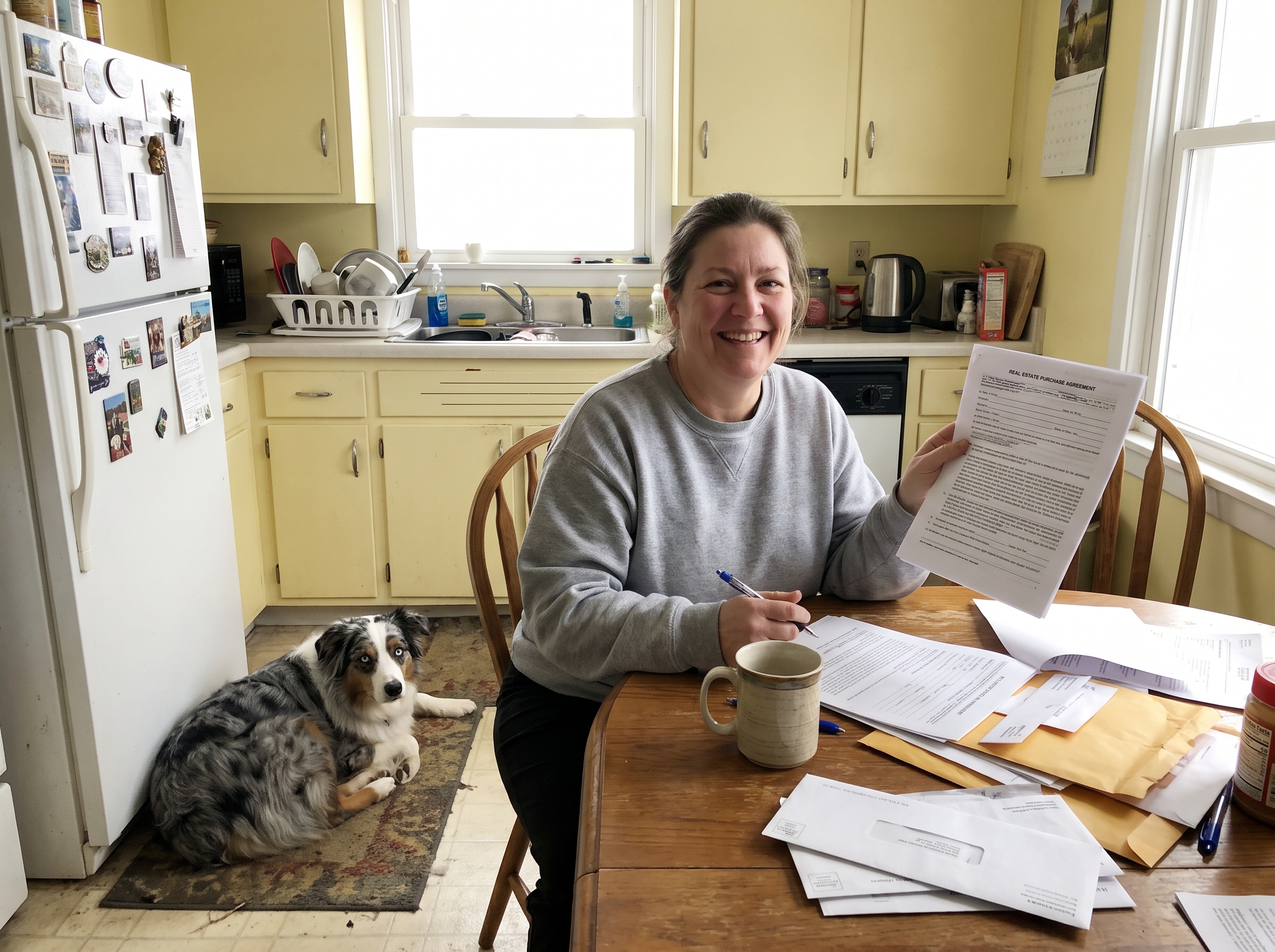 Woman signing real estate purchase agreement with Australian Shepherd